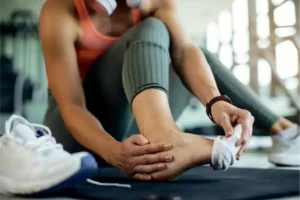 Persona deportista tocándose el tobillo por dolor o lesión, medicina del deporte y medicina integrativa para recuperación y prevención de lesiones.