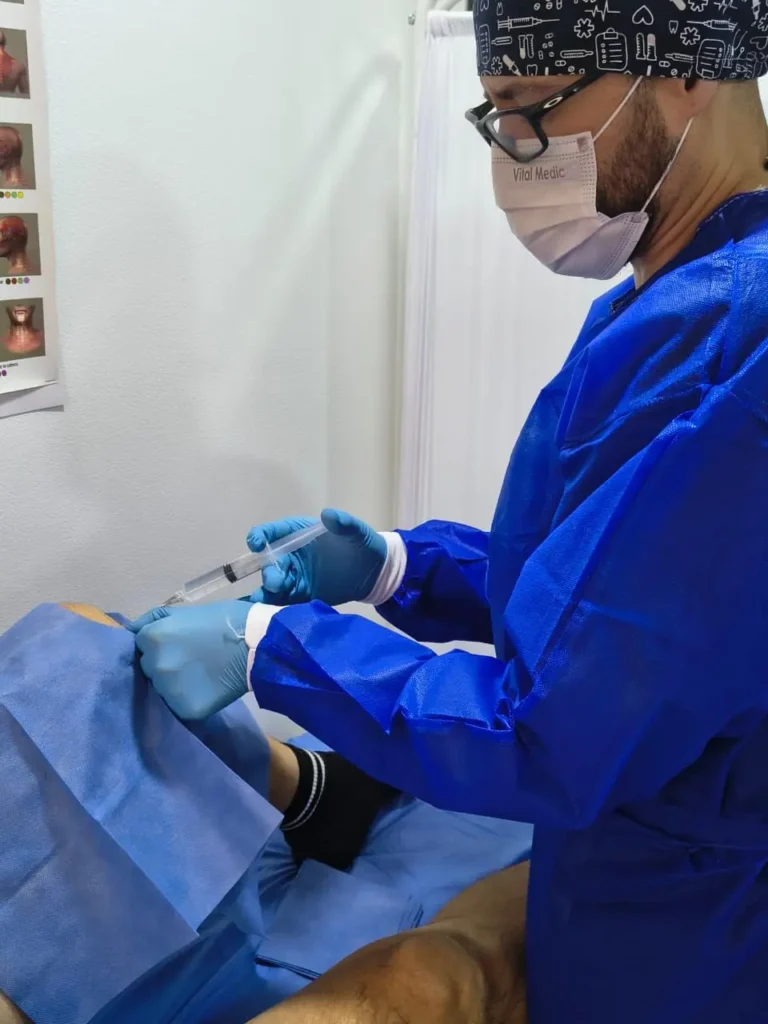Dr. Camilo realizando procedimiento de infiltración articular con protocolo de medicina regenerativa avanzada en la clínica Vitaconciencia Bogotá.